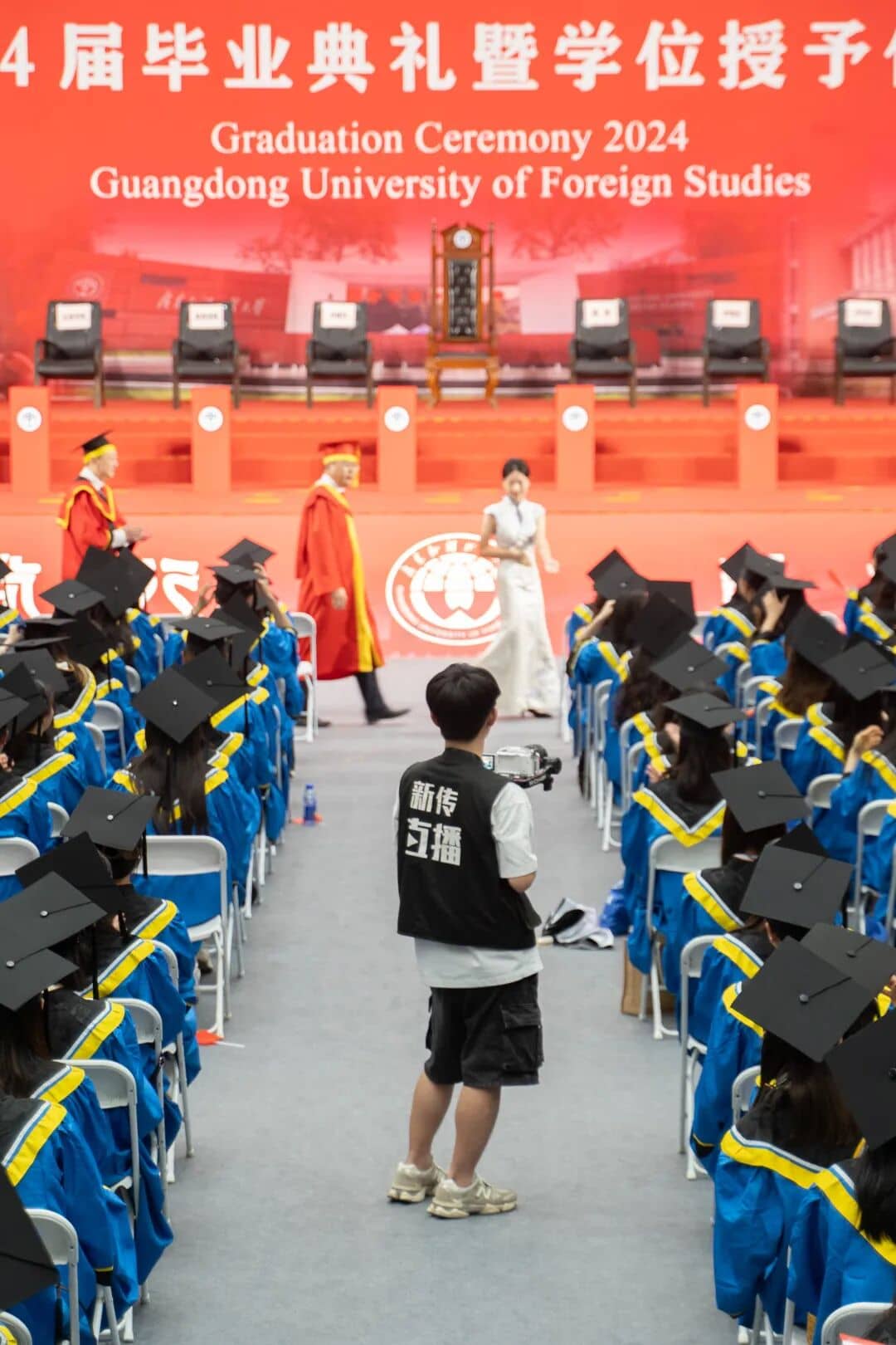 摄像成员在毕业生队列之间拍摄学位授予仪式